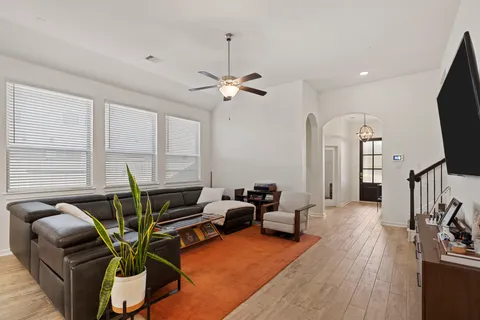 a living room with furniture a ceiling fan and a flat screen tv