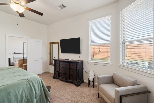 a spacious bedroom with a bed and a flat screen tv