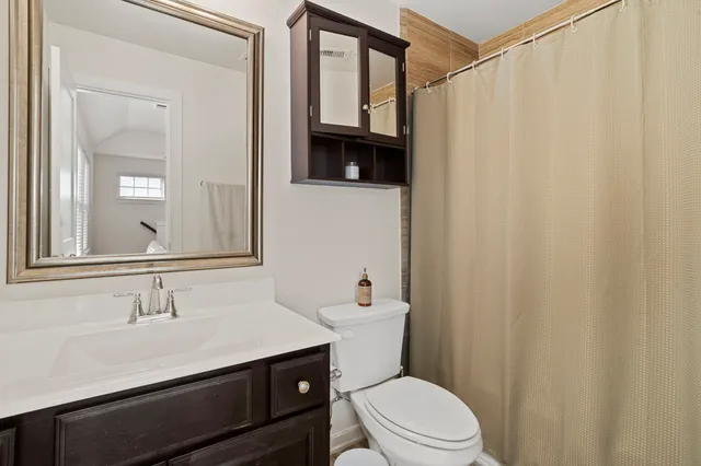 a bathroom with a sink a toilet a mirror and shower curtain
