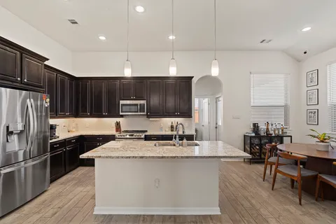 a kitchen with kitchen island granite countertop a sink refrigerator and cabinets