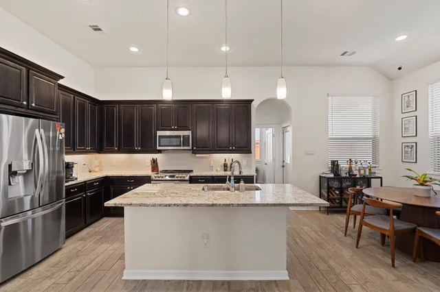 a kitchen with kitchen island granite countertop a sink refrigerator and cabinets