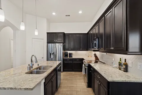 a kitchen with stainless steel appliances granite countertop a sink stove and cabinets