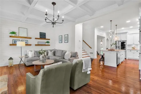 a living room with furniture kitchen view and a chandelier