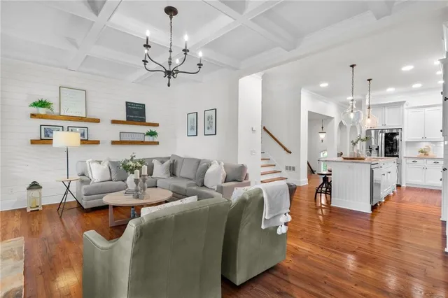 a living room with furniture kitchen view and a chandelier