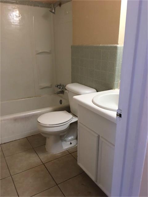 275 North 7th Street, Unit 5 Beaumont, TX 77702 - Photo 7 of 9 a white toilet sitting next to a white sink and vanity