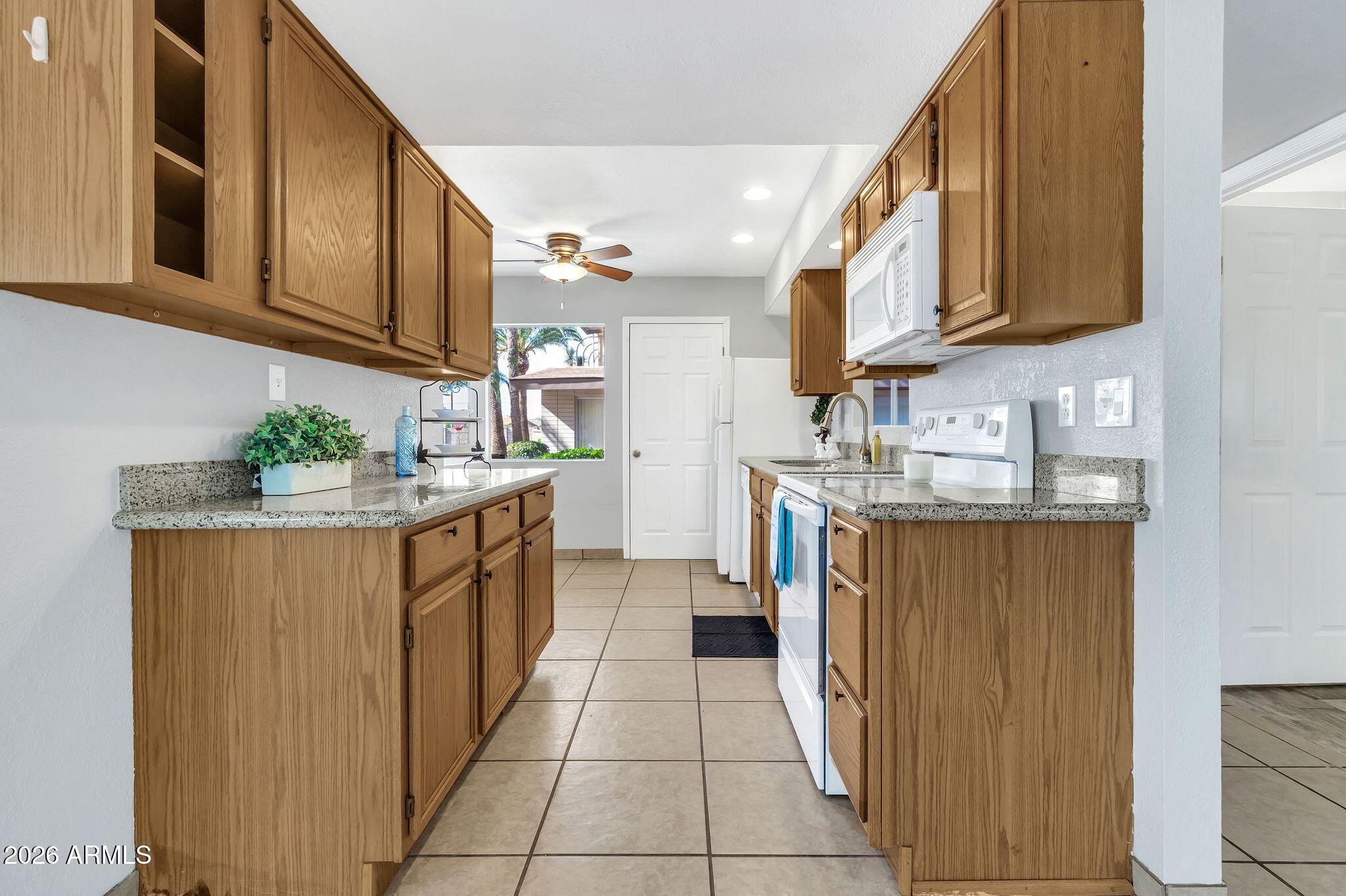 725 South Power Road, Unit 101 Mesa, AZ 85206 - Photo 6 of 38 a kitchen with stainless steel appliances granite countertop a stove a sink and a microwave