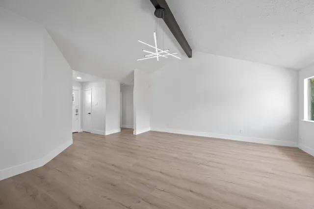 a view of an empty room with wooden floor and ceiling fan