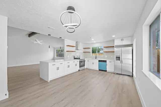 a kitchen with stainless steel appliances a white cabinets and wooden floors