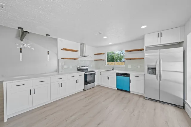 a large kitchen with cabinets wooden floor and stainless steel appliances