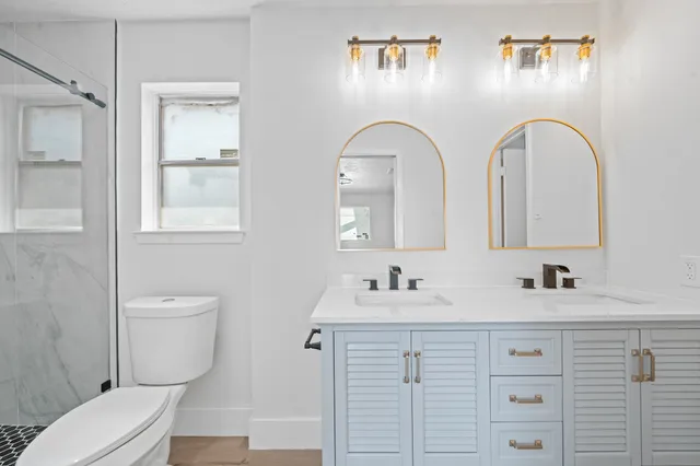 a bathroom with a double vanity sink a toilet and a mirror
