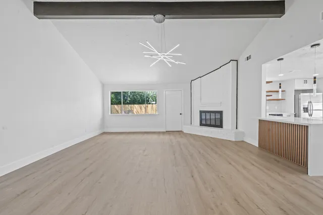 a view of an empty room with a window and a kitchen