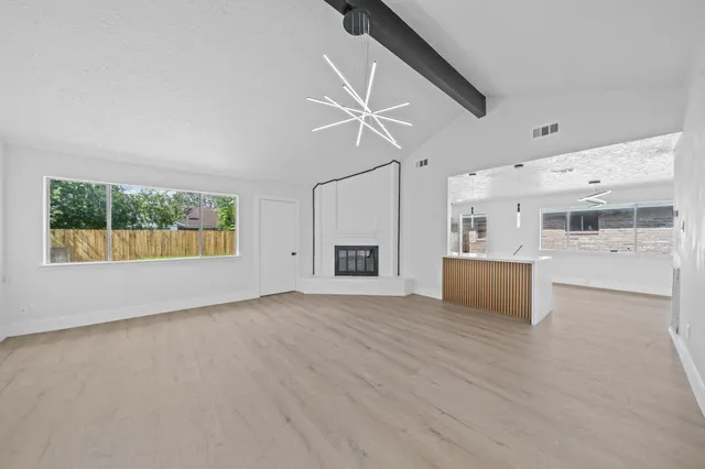a view of an empty room with a window and kitchen view