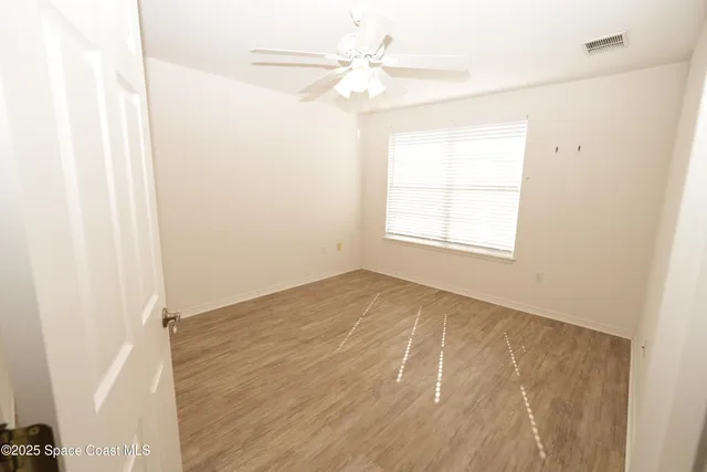 an empty room with a window and a fan