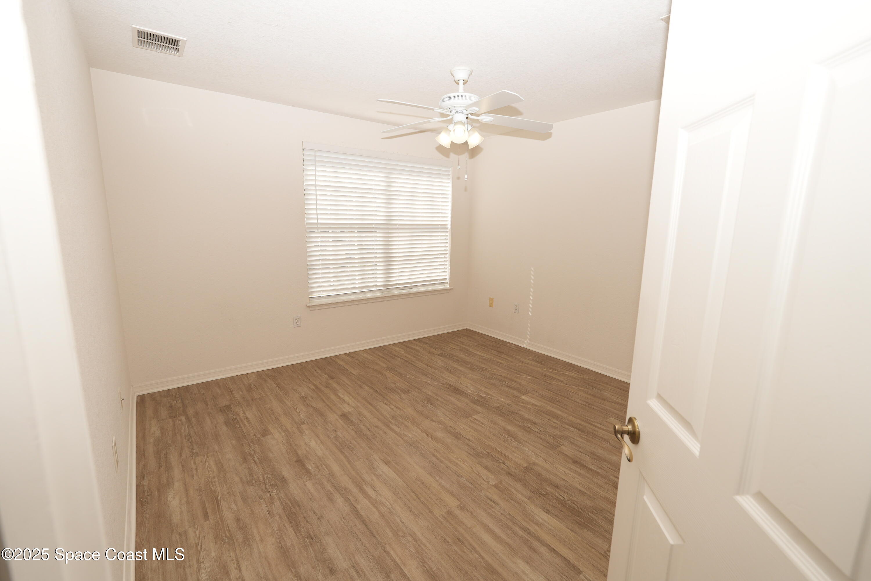 110 Turpial Way, Unit 103 Melbourne, FL 32901 - Photo 16 of 20 an empty room with wooden floor fan and windows