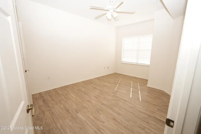 an empty room with a window and a ceiling fan