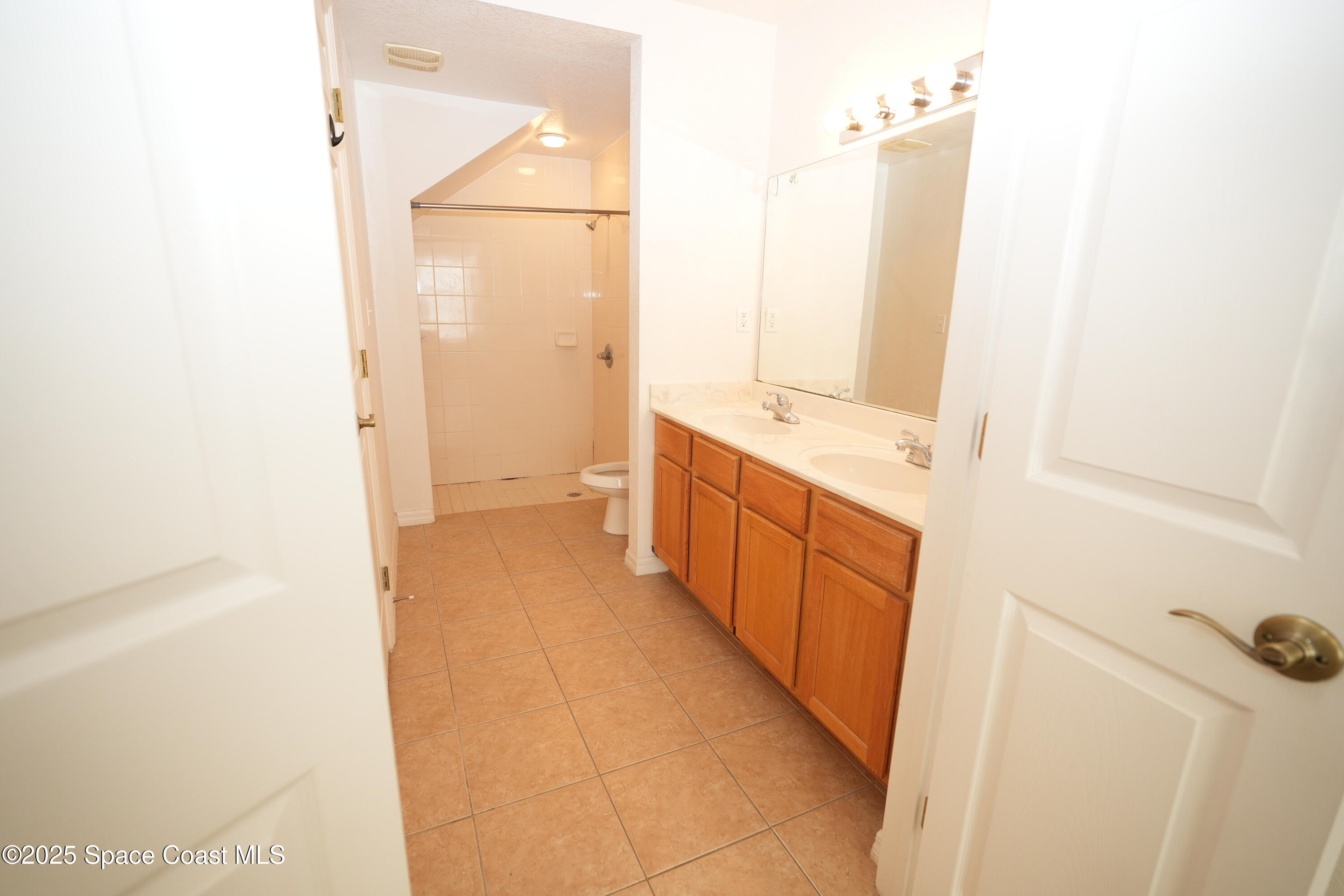 110 Turpial Way, Unit 103 Melbourne, FL 32901 - Photo 10 of 20 a bathroom with a double vanity sink and mirror