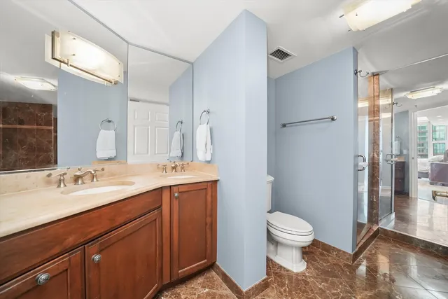 a spacious bathroom with a granite countertop sink toilet a large mirror a shower and a