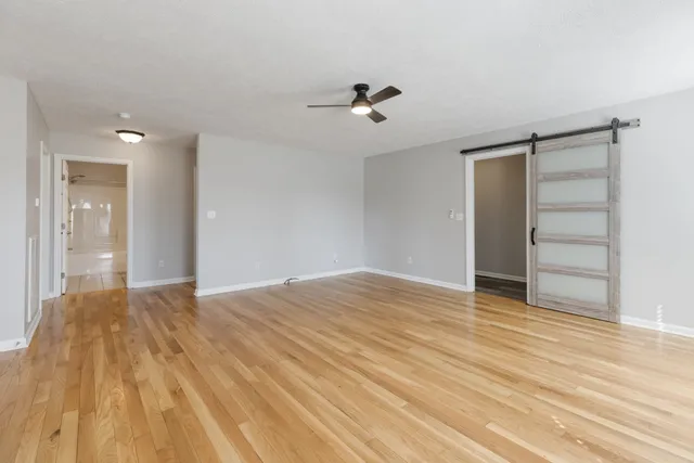 a view of empty room with wooden floor and fan
