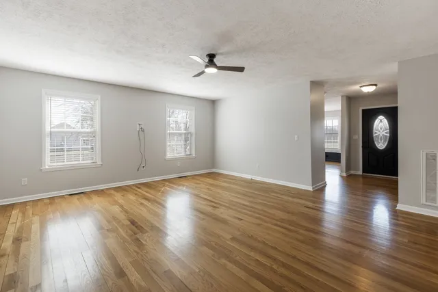 an empty room with wooden floor and windows