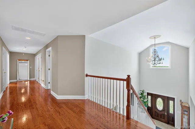 a view of a hallway to a room with wooden floor and windows