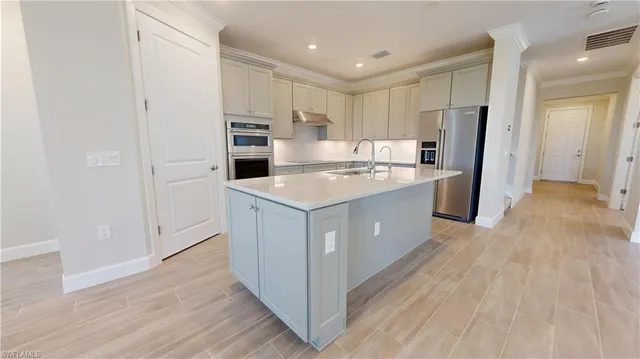 a kitchen with a refrigerator a sink and wooden floor