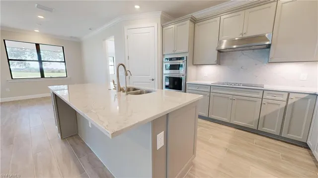 a kitchen with stainless steel appliances granite countertop a sink a stove and a wooden floors