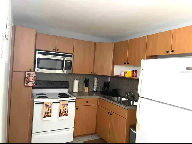 a kitchen with a refrigerator a stove top oven a sink and cabinets