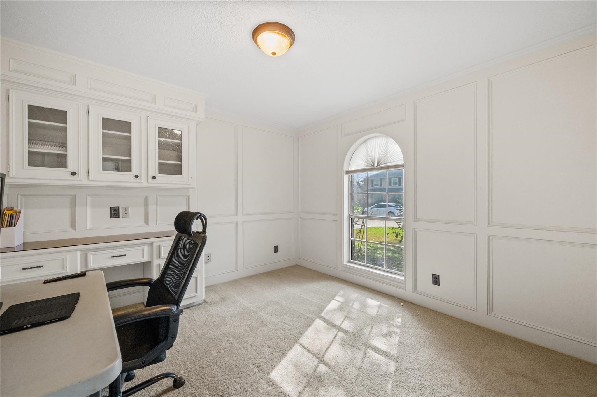 19702 Sweet Forest Lane Humble, TX 77346 - Photo 16 of 30 This home office features built-in cabinets, a large window with an arched top for natural light, and neutral carpeting, creating a functional and inviting workspace. It also could be a 5th bedroom as it has a clothes closets.