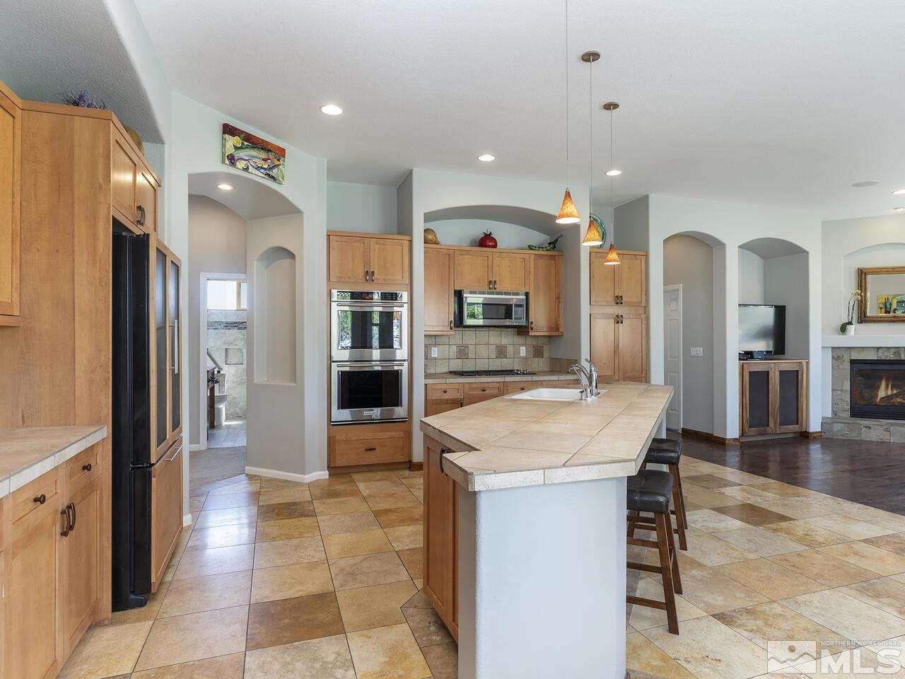 895 Peacepipe Loop Reno, NV 89511 - Photo 12 of 37 a kitchen with stainless steel appliances kitchen island granite countertop a refrigerator and cabinets
