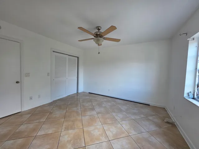 an empty room with windows and fan