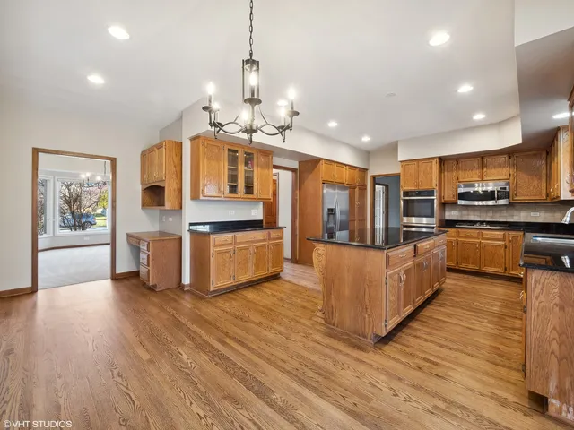 a large kitchen with stainless steel appliances granite countertop a oven and a view of living room