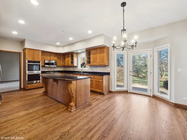 a large kitchen with stainless steel appliances granite countertop a stove and a wooden floors