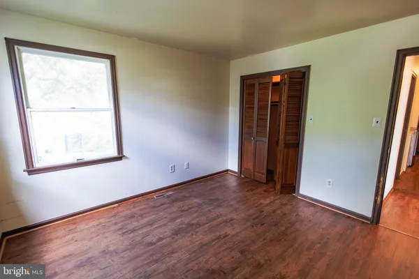 a view of empty room with wooden floor and closet