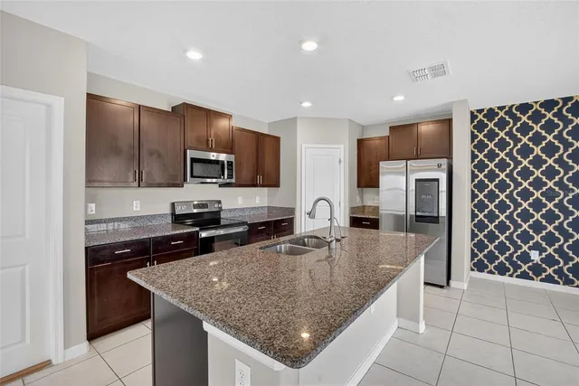 a kitchen with stainless steel appliances granite countertop a sink dishwasher stove top oven and refrigerator