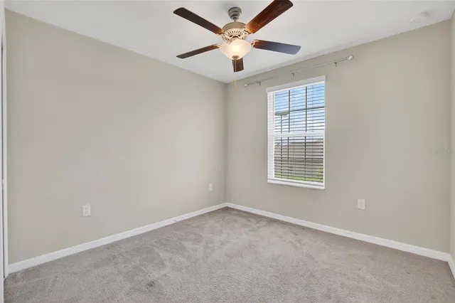 an empty room with a chandelier fan and closet area