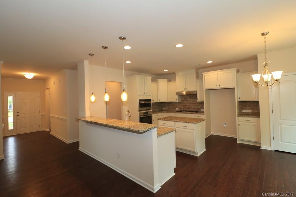 156 Hawks Creek Parkway, Unit 16 Fort Mill, SC 29708 - Photo 9 of 21 a kitchen with stainless steel appliances granite countertop a refrigerator a sink dishwasher a stove and a dining table with wooden floor