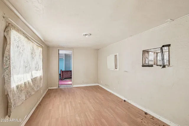 a view of an empty room with wooden floor and a window