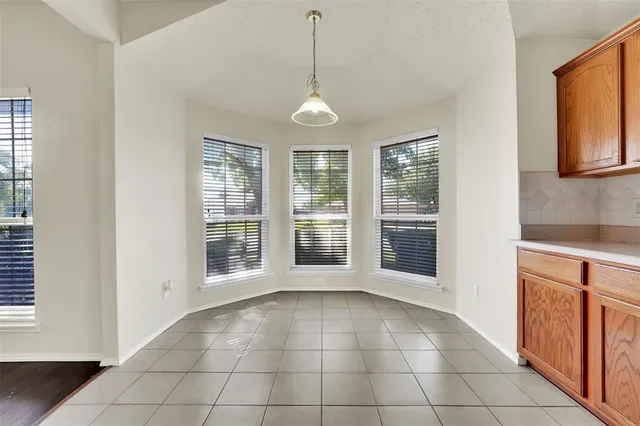 a view of an empty room with window and cabinet area