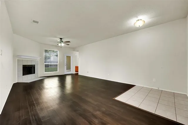 an empty room with wooden floor fireplace and windows