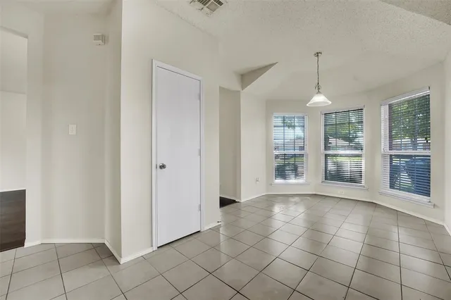a view of an empty room with window and chandelier