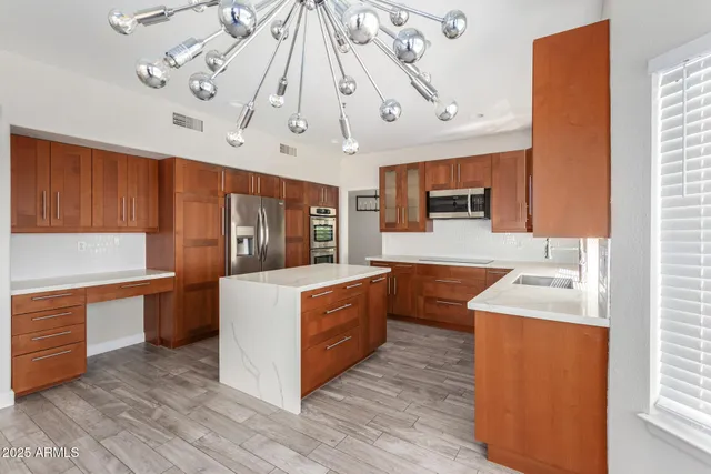 a large kitchen with a stove a sink dishwasher and a refrigerator with wooden floor