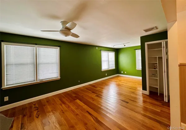 a view of an empty room with window and wooden floor