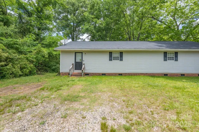 a front view of house with yard and trees in the background