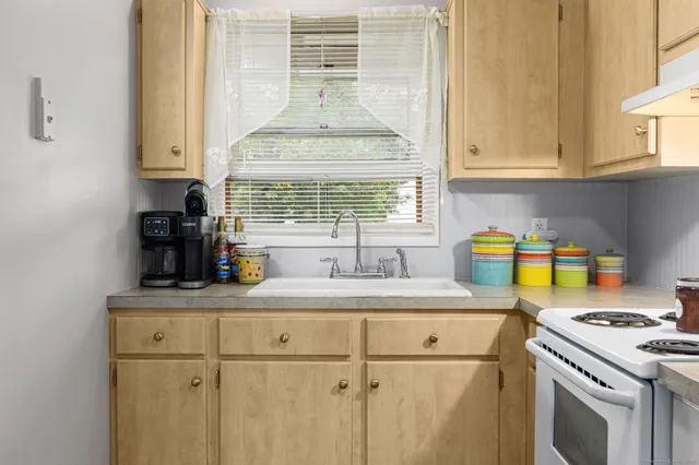 a kitchen with kitchen island granite countertop a sink cabinets a window and stainless steel appliances