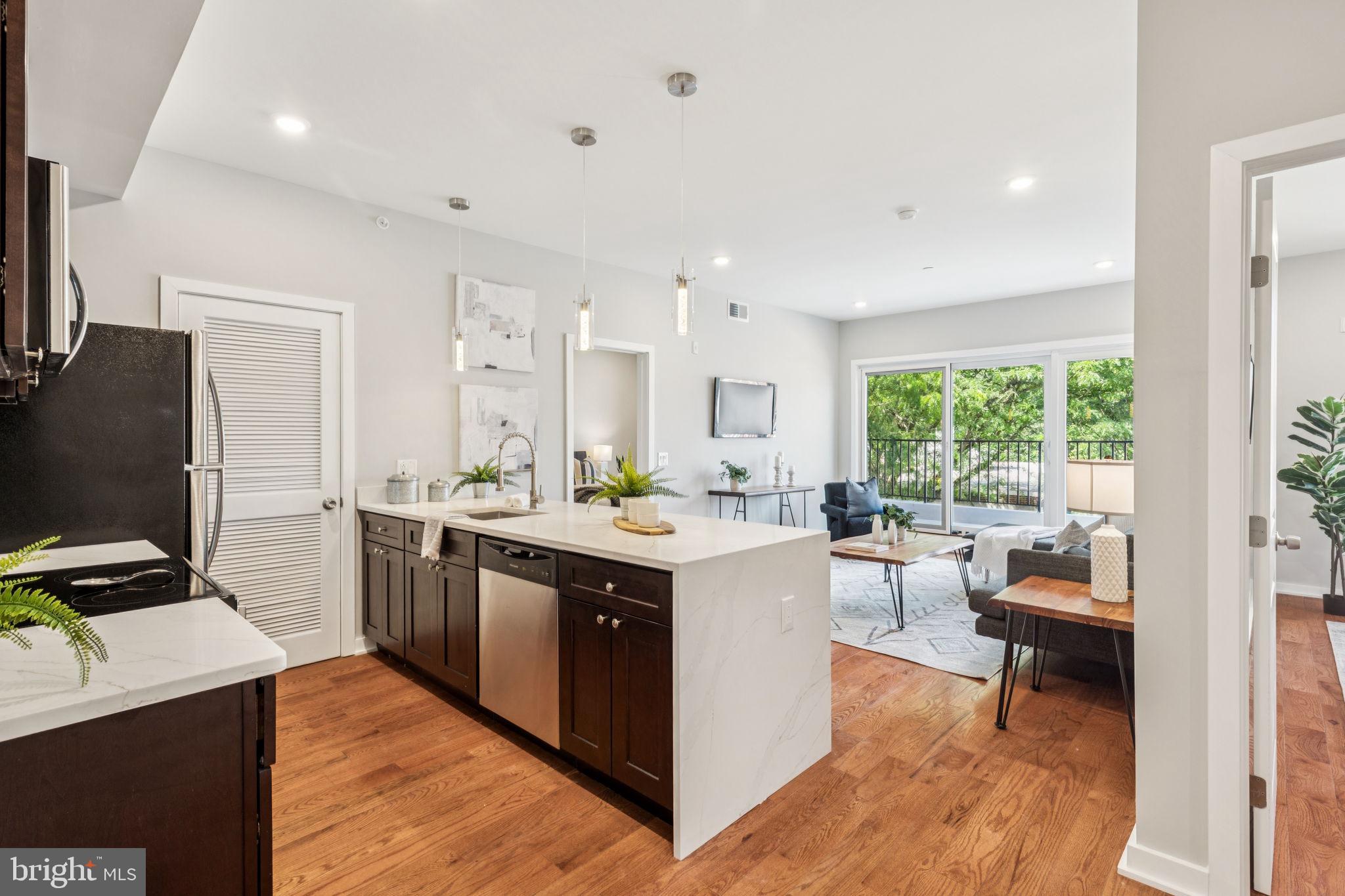 203 Haverford Avenue, Unit 208 Narberth, PA 19072 - Photo 2 of 35 a kitchen with a stove a refrigerator a sink dishwasher with a dining table and chairs with wooden floor