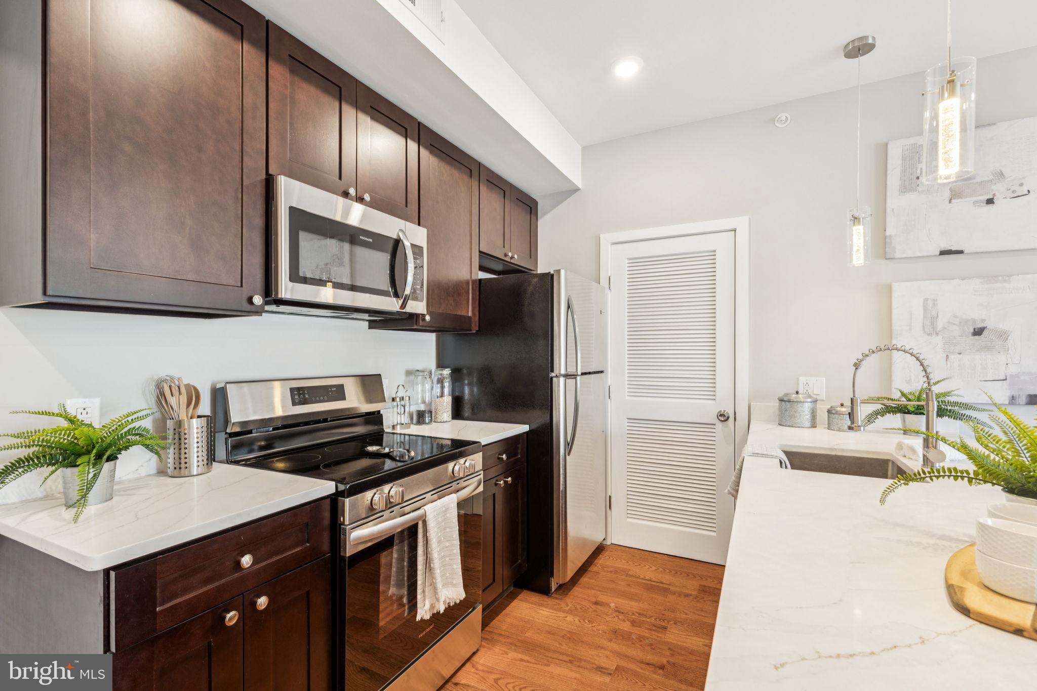 203 Haverford Avenue, Unit 208 Narberth, PA 19072 - Photo 6 of 35 a kitchen with kitchen island granite countertop a sink a stove cabinets and refrigerator