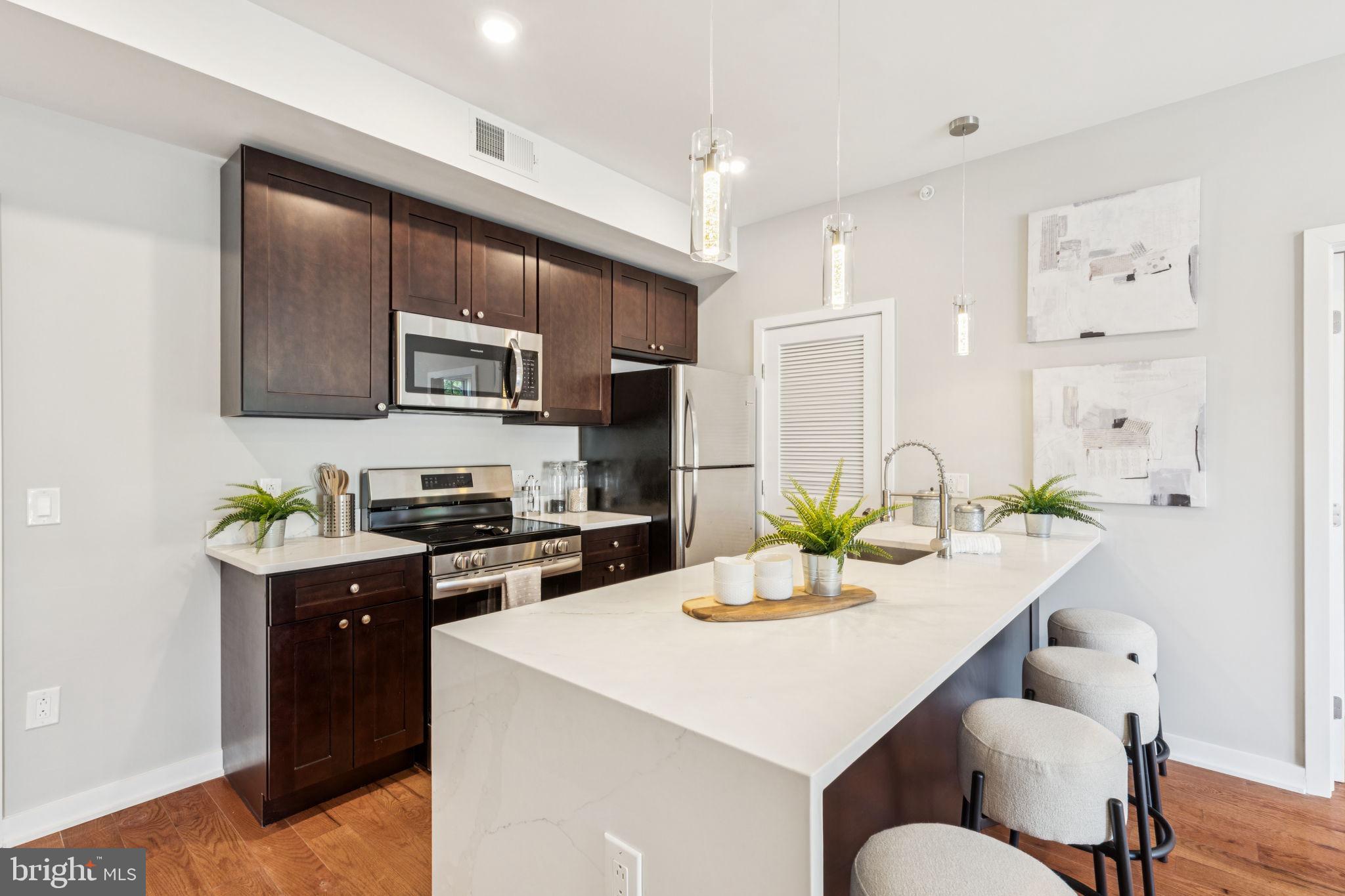 203 Haverford Avenue, Unit 208 Narberth, PA 19072 - Photo 8 of 35 a kitchen with a stove a sink a kitchen island with a dining table and chairs