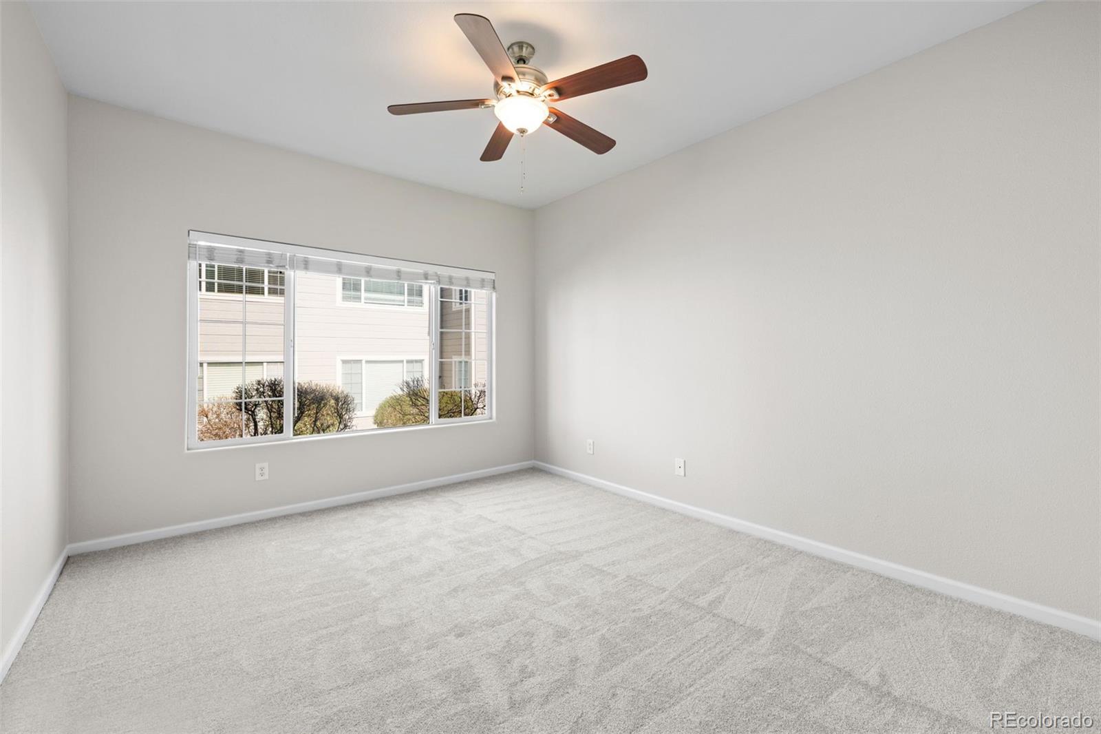 8389 Pebble Creek Way, Unit 101 Highlands Ranch, CO 80126 - Photo 14 of 44 an empty room with a window and a ceiling fan