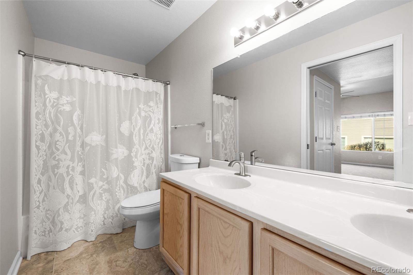 8389 Pebble Creek Way, Unit 101 Highlands Ranch, CO 80126 - Photo 16 of 44 a bathroom with a double vanity sink toilet and a mirror
