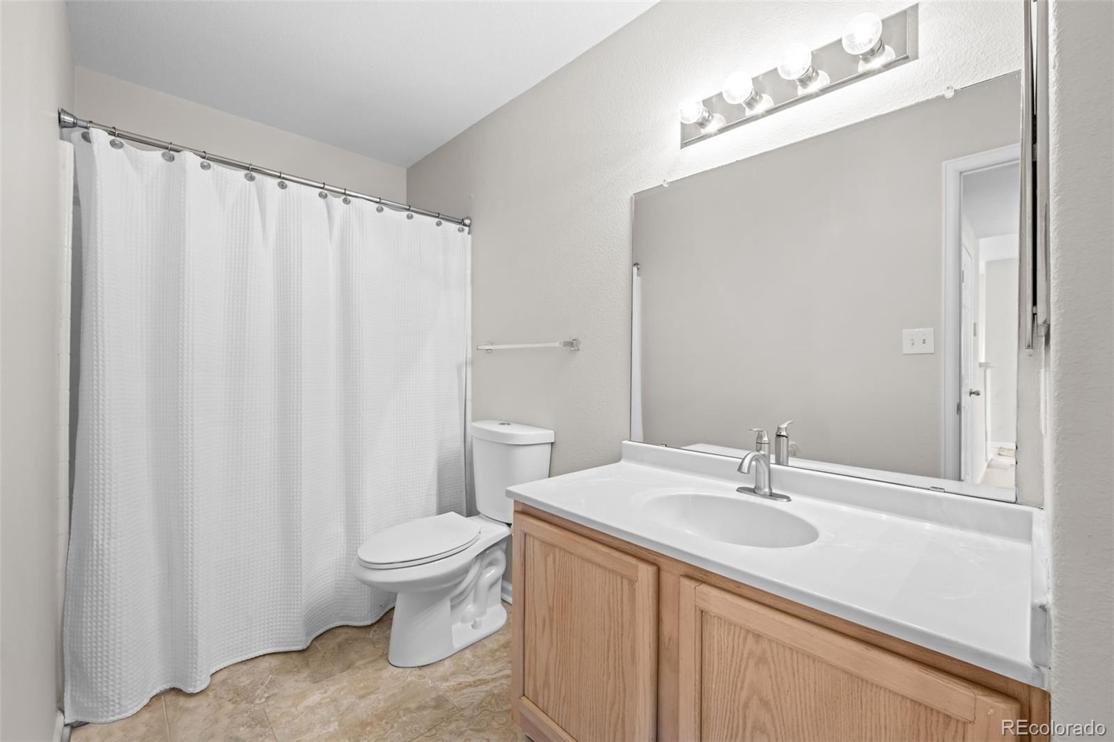 8389 Pebble Creek Way, Unit 101 Highlands Ranch, CO 80126 - Photo 22 of 44 a bathroom with a sink a toilet and shower curtain